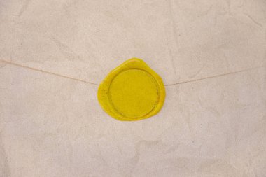 Kırışık kahverengi el işi kağıt zarfının üzerini kapayın ve boş sarı balmumu mühür tasarlayın..