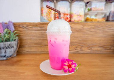 Tayland 'da buzlu pembe süt favori içeceği. Tatlı içecek kırmızı şeker şurubu. Plastik bardakta taze süt ve süt köpüğü. Kahve servisi için içecek menüsü..