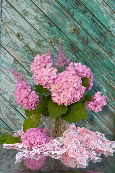 Ramo de naturaleza muerta con hortensias rosadas y astilba en la silla vieja con mantel de ganchillo casero — Foto de Stock