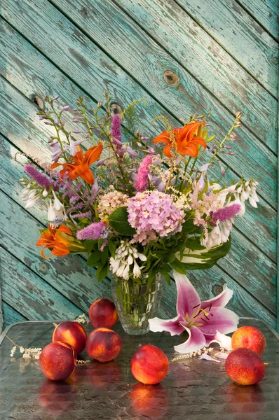 Still life bouquet of hosta, astilbe, hemerocallis, pink hydrangea and nectarines. Nectarines and lily on the table. — Stock Photo, Image