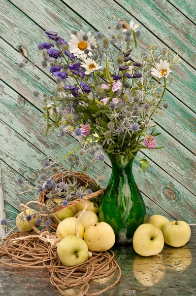 Bodegón flores silvestres ramo en un jarrón verde con manzanas —  Fotos de Stock