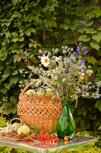 Still life with basket of apples and wild flowers bouquet — Stock Photo, Image