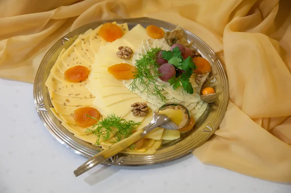 Серебряная тарелка с нарезанным сыром — стоковое фото