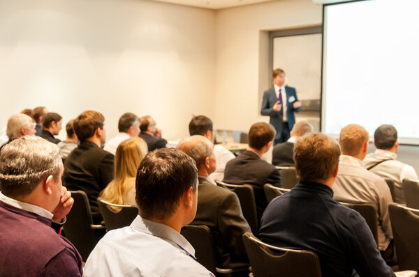 People sitting at the business conference and speaker at the screen