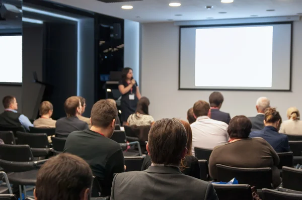 Business conference. people sitting rear and woman speaking at the screen — Stock Photo, Image