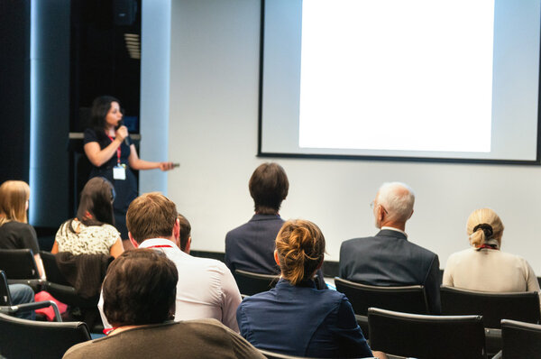 Business conference. people sitting rear and woman speaking at the screen