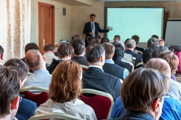 Conférence d'affaires. personnes assises à l'arrière et haut-parleur expliquant à l'écran — Photo