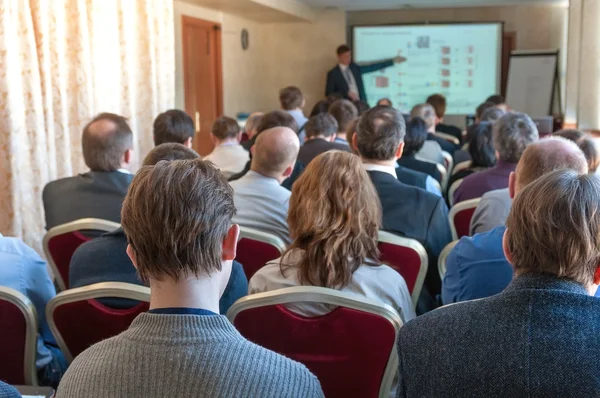 Conferenza d'affari. persone sedute dietro e altoparlanti che spiegano sullo schermo Foto Stock Royalty Free