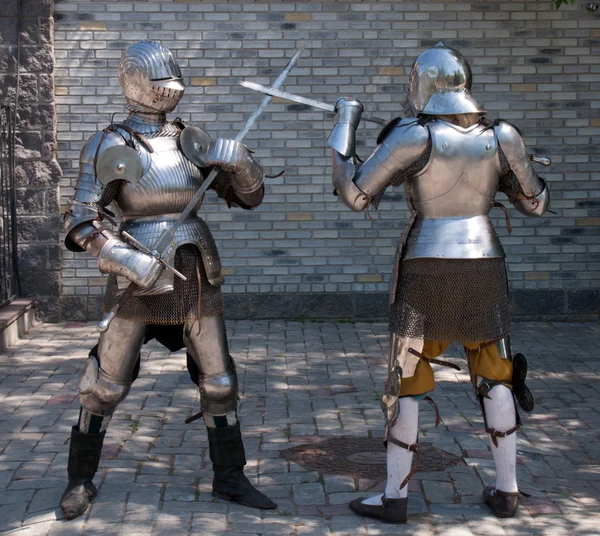 Two knights in the ancient metal armor standing near the stone wall — Stock Photo, Image