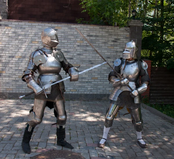 Dwóch rycerzy w antyczny metalowy pancerz stojący w pobliżu ściany z kamienia — Zdjęcie stockowe