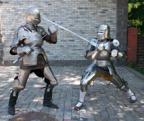 Два рыцаря в старинных металлических доспехах стоят у каменной стены — стоковое фото