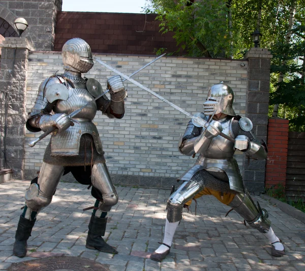 Two knights in the ancient metal armor standing near the stone wall — Stock Photo, Image