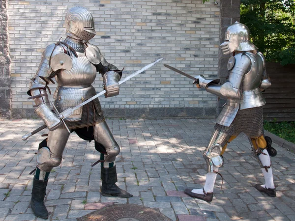 Two knights in the ancient metal armor standing near the stone wall Stock Picture