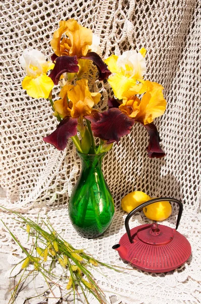 Bouquet nature morte aux iris rares jaunes et marron dans un vase vert et une théière — Photo