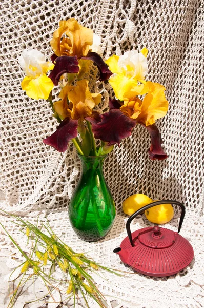 Buquê de natureza morta com íris raras amarelas e marrons em um vaso verde e panela de chá — Fotografia de Stock