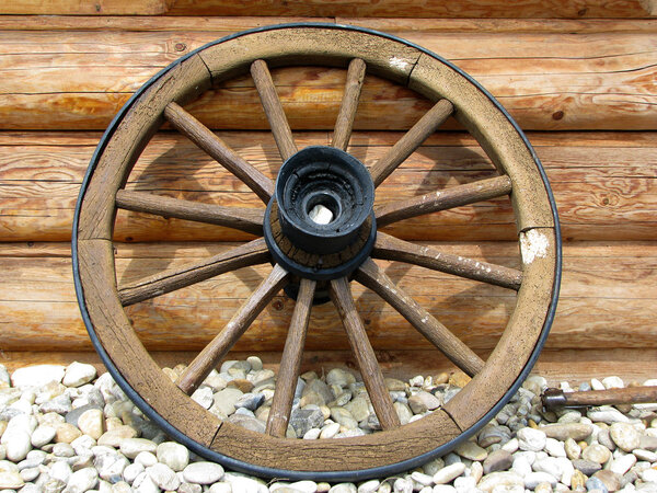old wagon wheel side by wooden wall
