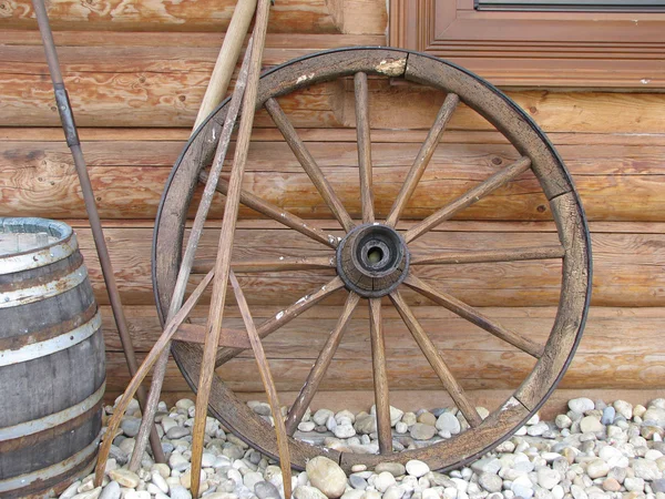 Старое колесо прислонилось к деревянной стене — стоковое фото