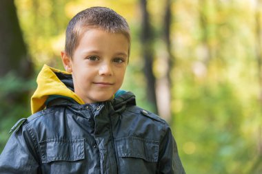 Ormanda kameraya gülümseyen bir çocuğun portresi..