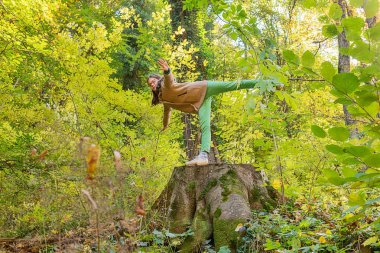 Sonbahar parkında bir kız kütüğün üzerinde duruyor..