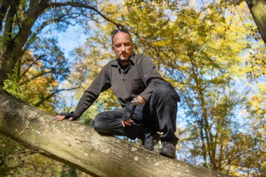 Adam ağaca tırmandı. Bir sonbahar ormanında ağaçta oturan adam