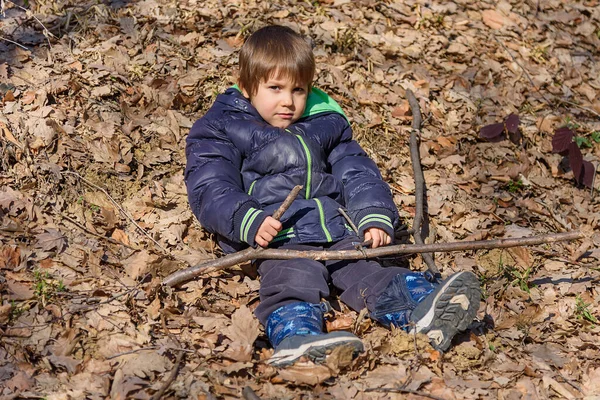 Çocuk ormanda bir yaprağın üzerinde yatıyor. Sarı sonbahar yapraklı küçük çocuk parkta
