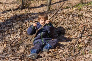 Çocuk ormanda bir yaprağın üzerinde yatıyor. Sarı sonbahar yapraklı küçük çocuk parkta
