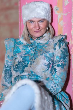 Kışlık paltolu ve kışlık şapkalı (Ushanka) güzel bir kadın. Terk edilmiş bir kalede güzel bir kadın..