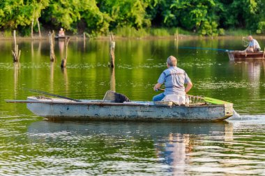 Novi Sad, Sırbistan - 06 Temmuz 2022: Sırbistan 'ın Novi Sad kenti yakınlarındaki Tuna Adası (Sodros). Balıkçılar kayıkta oturup olta tutuyorlar..