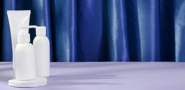 Cilt güzellik kozmetik konsepti. Mavi arka planda beyaz krem losyon temizleyici antioksidan yüz yağı, kopyalama alanı, afiş.