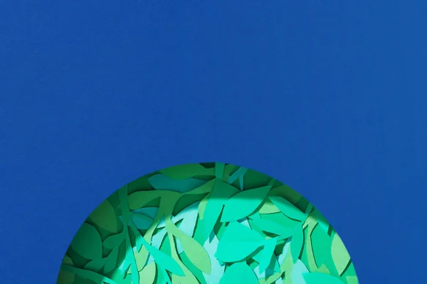 Merkezdeki kağıttan gezegende yeşil yapraklar. Dünya gününü kavra, gezegen kartını kurtar, boşluğu boşalt