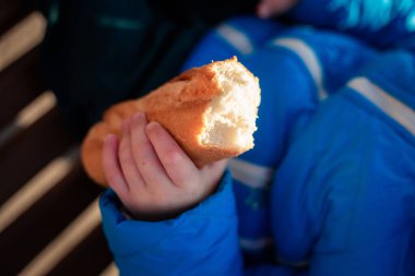 Çocuk elinde bir çörek tutuyor.