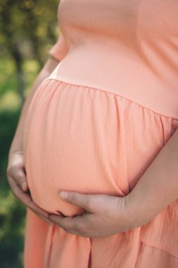 pregnant girl in pink holds her belly