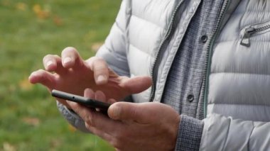 Erkek eller akıllı telefon tutuyor, yakın plan. Kimliği belirsiz bir adam iş ortağına mesaj gönderiyor.