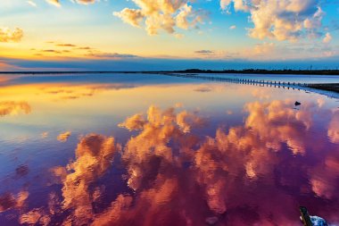 Tuz gölünün üzerinde parlak bir gökyüzü var ve bulutlar suya yansıyor. Ufuk yoğun kara bulutlarla kaplıdır.