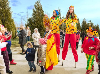 Maslenitsa 'nın halk ile iletişimi kutlamaları sırasında ayaklık takan soytarı kostümlü sanatçılar