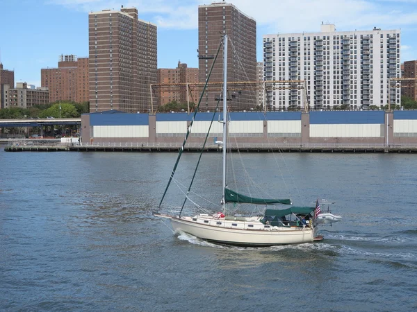 Yacht Traveling along blue open water with beautiful sky against New York City Apartment Background — Stock Photo, Image