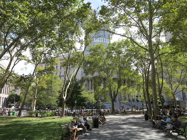 Los neoyorquinos disfrutan de un hermoso día en el parque de la ciudad con edificios de oficinas gubernamentales y tribunales —  Fotos de Stock