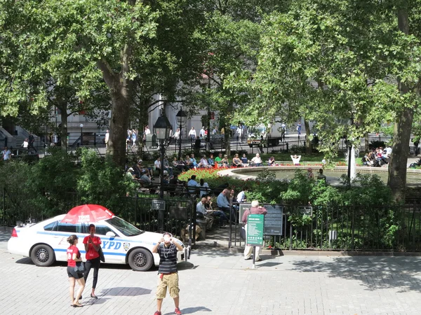 New york city radiowóz siedzi bezczynnie, podczas gdy ludzie cieszyć się w letni dzień na bowling green park w Nowym Jorku — Zdjęcie stockowe