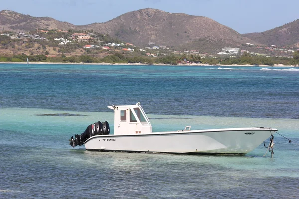Моторная лодка или рыболовное судно сидит без дела на спокойных голубых водах Карибского моря в Санкт-Мартине — стоковое фото