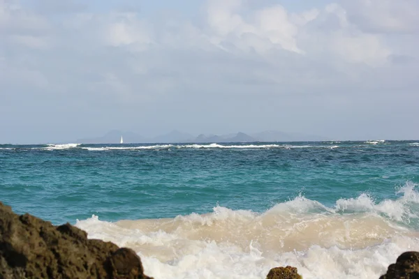 Seascape fale i błękitne niebo i Morze Karaibskie z cajon rock od brzegu plaży dawn beach w st. martin — Zdjęcie stockowe