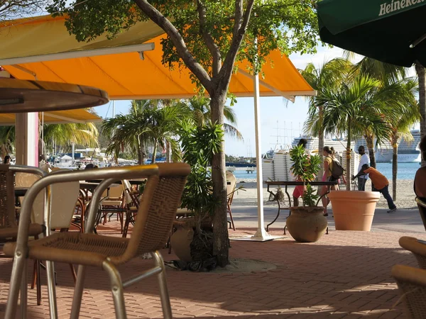 Un bar restaurante vacío que bordea la playa en Philipsburg St. Maarten con turistas y lugareños en el fondo —  Fotos de Stock