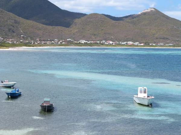 Pequeños barcos a motor se sientan ociosos con tranquilas aguas azules del Caribe y el telón de fondo del volcán extinto en St. Maarten —  Fotos de Stock