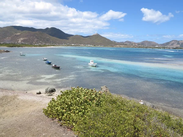 Små motorbåter sitter uvirksomme med stillestående blått vann i det karibiske og utdødde vulkanbakteppet på St. Maarten – stockfoto