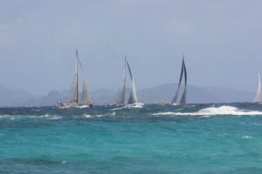 Sail Boats of the Heineken Regatta Navigate choppy Atlantic Ocean offshore at Dawn Beach in St. Maarten clipart