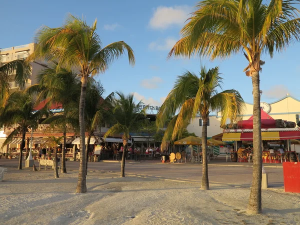 Boardwalk in Philipsburg, St. Maarten is lined with restaurants, bars, and tourists while sun set approaches — Stock Photo, Image