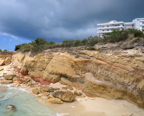 New Mall in the distance while storm front moves over the beautiful sandstone formations along Cupecoy beaches in St. Maarten