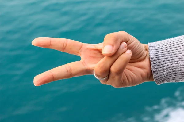 Mulher mostrando dois dedos isolados no fundo mar samui — Fotografia de Stock
