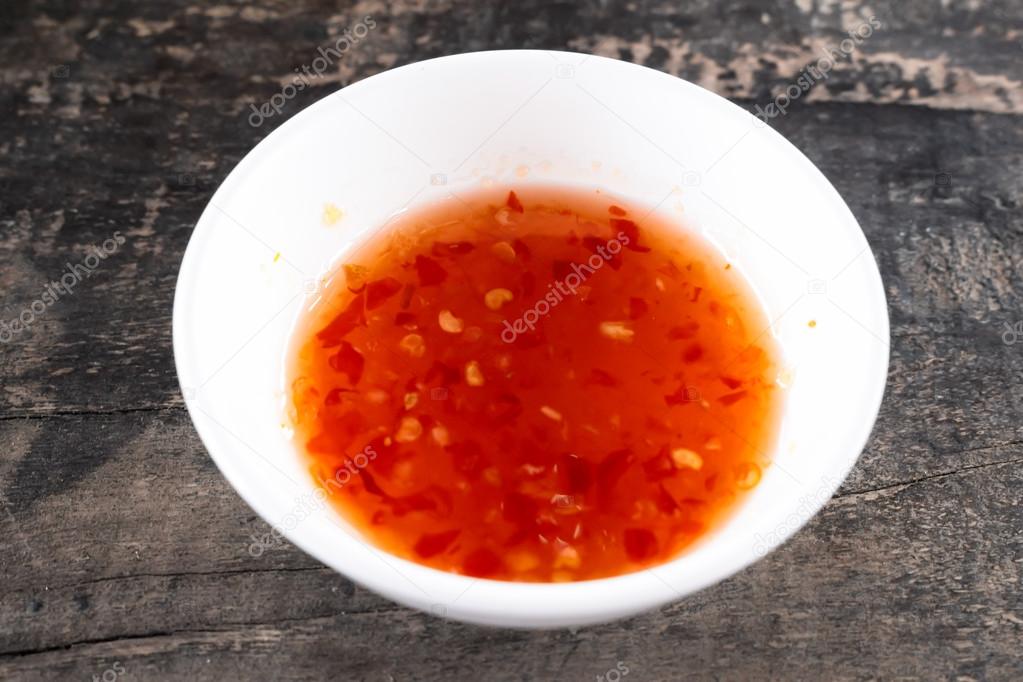 Sweet chilli dipping sauce with white cup paste on wooden table Stock