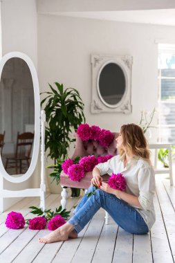 Gömlekli ve kotlu bir kadın elinde şakayık buketi tutuyor. Güzel sarışın kadın portresi. Randevu için sürpriz bir buket çiçek, anneler günü ya da sevgililer günü