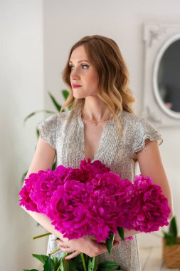 İş kadını çiçekçi atölyede çiçek buketi yapıyor. Girişimci elinde pembe şakayık buketi tutuyor.